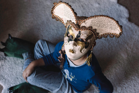 Child plays with a full Venetian maskの写真素材