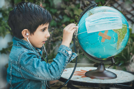 Child plays to listen to a globe in the garden at home.