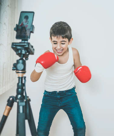 Boy practices boxing while recording with a mobile phoneの写真素材