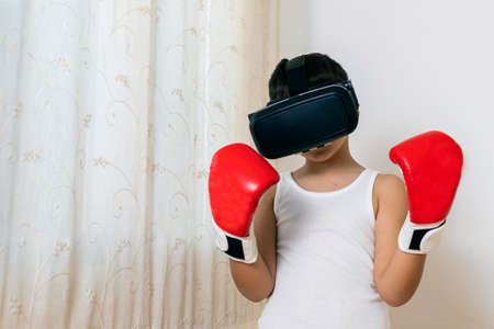 Boy with virtual reality glasses takes boxing lessons from a distance