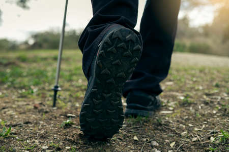 Shot of a hiker's feet with a technical trekking pole on a field tripの写真素材