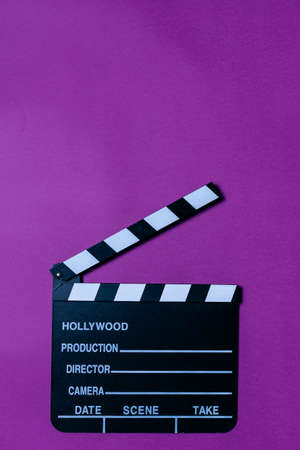 Movie clapperboard on purple background with copy space