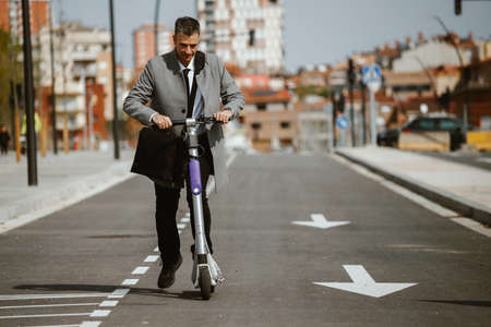 Elegant businessman with electric scooter in the cityの写真素材