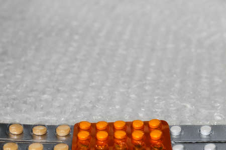 Trendy modern minimalistic background of orange beige white pills blister.Bubble bag background. Packages of tablets in blisters are arranged horizontally. Frame for design. Selective focus.の写真素材