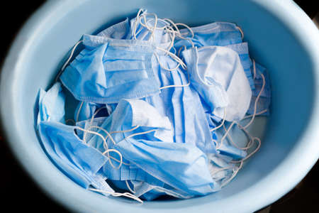 Top view of many stacked medical blue masks. A lot of used crumpled protective medical masks on a...