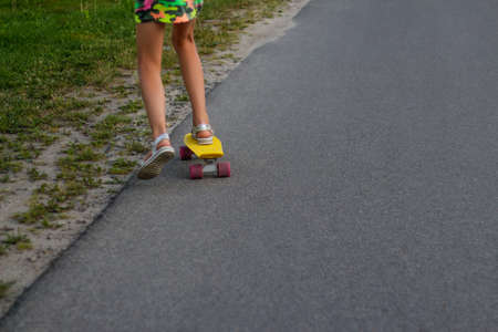 Defocus girl playing on yellow skateboard in the street and roadside. Caucasian kid riding penny...
