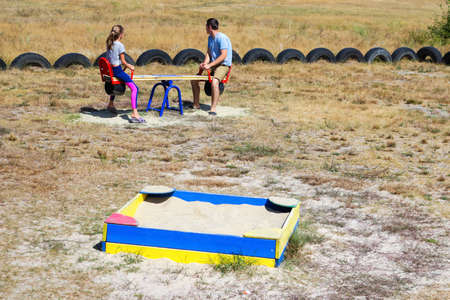 Defocused brother riding sister on back. Portrait of happy girl on man shoulders, piggyback. Girl fly, raise hand. Family playing outside. Green tree background. Man talking. Out of focus.の写真素材