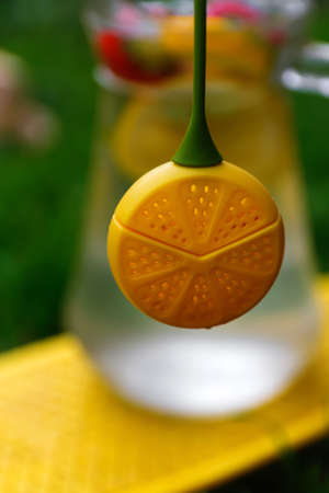 Defocus dummy lemon hanging over glass jug of lemonade with slice lemon and leaves of mint on...