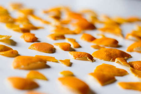 Defocus close up modern trendy bright Christmas background from the peel of the peels of orange and tangerine. On a white background. Many small pieces of dried orange peel. Pattern. Out of focus.の写真素材