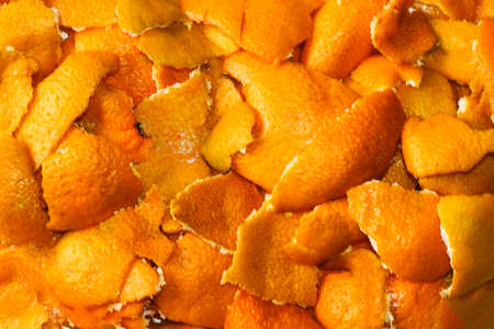 Close-up blurred background of dried orange and tangerine skins. Lots of small pieces of dried orange peel, stacked together. Bright orange background, backdrop. Good New Year spirit. No focus.の写真素材