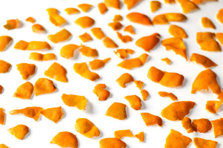 Modern trendy bright Christmas background from the peel of the peels of orange and tangerine. On a white background. Many small pieces of dried orange peel. Pattern. Selective focus.の写真素材