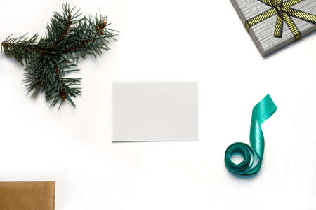 Blank white Christmas Card. gift cover. Christmas composition. Paper blank, christmas tree branches, gift decorations on white background. Flat lay, top view, copy space, square. Selective focus.の写真素材