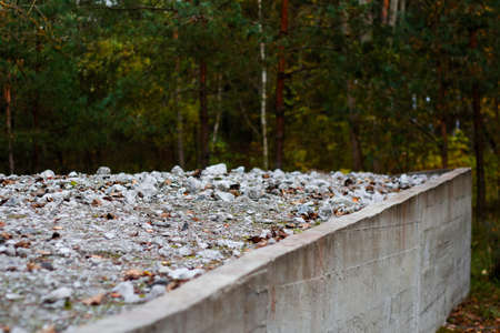 Defocus many crushed stones in mound or memorial. Gravel of jews people. White rock, minerals, archeology, excavations on concrete slab. Outdoor, outside. Pine forest. Out of focus.の写真素材