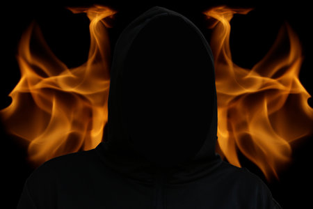 Death suit. An impersonal black robe with a hood, a symbol of death. Halloween concept. A bright glowing background with tongues of flame and fire. Selective focusの写真素材