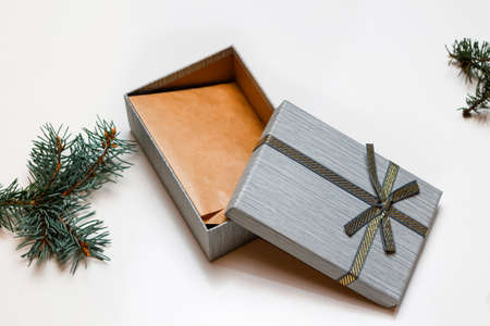 Defocus open gift box with craft envelope inside, Christmas tree branch on white background. Gold bow. Empty gift box. Out of focus.の写真素材