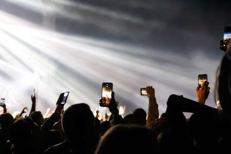 Volodymyr, Ukraine - 21.08.2021: defocus many people holding smart phone on rock concert and doing...