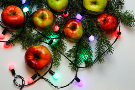 Many red and yellow organic apples on festive christmas tree background with bulb light. Food and diet. Healthy fruit background. Vitamin composition. White backgroundの写真素材