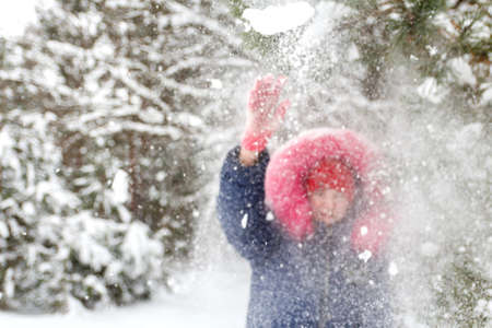 Portrait of preteen happy girl in red warm hat posing outside on nature winter snowy forest...