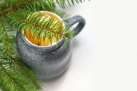 Close-up mug of lobule orange mandarin or tangerine on green natural fir tree branches background .. Creative Christmas hot drink. Holiday mood. Art Christmas concept. Copy space.の写真素材