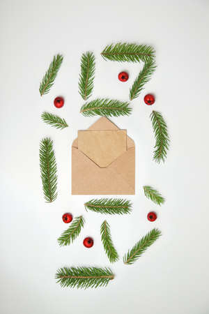 Beige craft envelope, letter to Santa. Frame of fir branch or spruce branch and red berries isolated on white background. Fir tree branches. Christmas greeting card. Template for design. Vertical.の写真素材