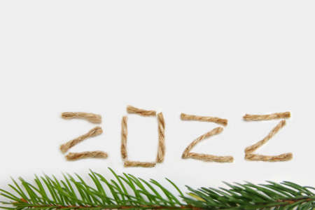 2022. Happy New year 2022. New Year Concept welcoming New Year 2022 written by craft rope or jute on white background. Two thousand twenty two. Border. Isolated. Close-up. Green fir branchの写真素材