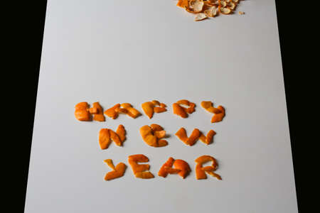 Happy New Year. Defocus New year word displayed by orange dry peel on a gray background. Decoration for New Year. Greeting card Text and DIY letters. Border. Diagonal view. Black border. Out of focus.の写真素材