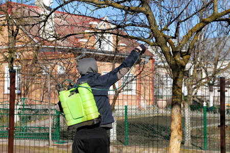 Fumigating pests, pest control. Defocus farmer man spraying tree with manual pesticide sprayer...