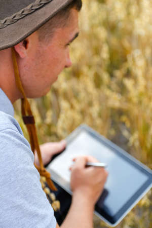 Music hobby. Young beautiful caucasian man holding ukulele outside. Handsome hipster guy plays...