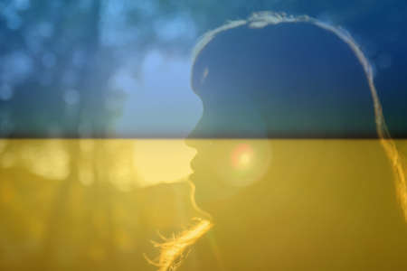 War Ukraine. Close-up silhouette of woman looking at sunrise. Mental health, hope, happiness concept. Dreams. Peace lifestyle. Open mind, new goals and decisions. Sunlight in fall park or forest.の写真素材