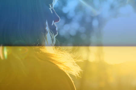 War Ukraine. Close-up silhouette of woman looking at sunrise. Mental health, hope, happiness concept. Dreams. Peace lifestyle. Open mind, new goals and decisions. Sunlight in fall park or forest.の写真素材