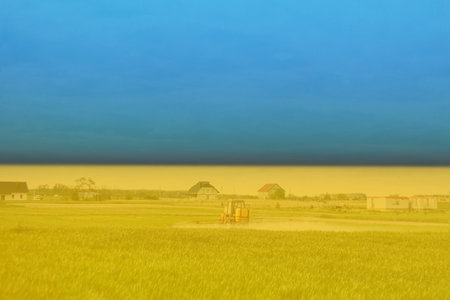 War Ukraine. Ukrainian flag. A tractor, farm machinery sprays insecticide a green corn wheat field...