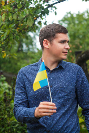 Ukrainian man. Young man holding ukrainian flag. No war. Support for Ukraine. Patriotic Spirit rising hand of Ukraine flag. freedom ukraine. Nature background. Verticalの写真素材