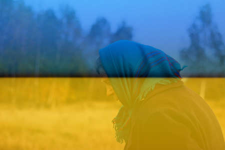 Defocus portrait of russian grandmother senior old woman standing in yellow autumn park. Ukraine ornament. Old women in coat and shawl. Sad person. Nature background. Out of focus.の写真素材