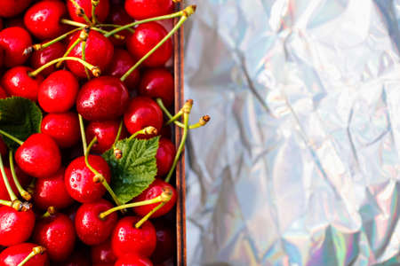 Defocus close-up cropped box, crape of dark red wet sweet cherries with tail and leaves on white background. Summer fruits and berries. Harvest and crop concept. Organic, eco. Copy space Out of focus.の写真素材