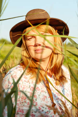 Defocus outdoor portrait of a beautiful blonde middle-aged woman near reed and pampas grass. Youth, love, fashion, romantic and lifestyle concept. 40s woman on nature background. Out of focus.の写真素材