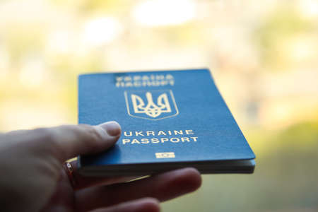 Defocus passport of a citizen of Ukraine in a female hand on a blurred urban background, close-up....