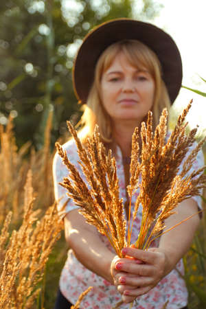 Defocus teen or preteen girl walking on nature background. Little kid girl holding bunch of pampas grass and showing it. Green meadow. Hipster. Portrait sunglasses. Out of focus.の写真素材