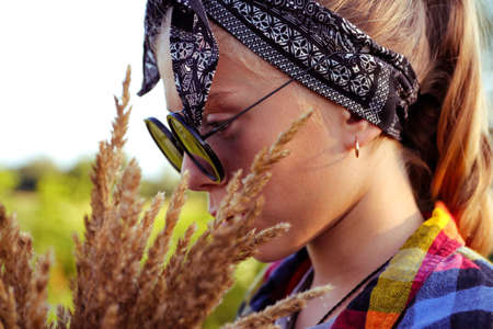 Defocus teen or preteen girl walking on nature background. Little kid girl holding bunch of pampas...