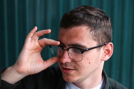 Defocus young man holding phone. Man using smart phone in autumn park. Typing text message or reading social media at mobile phone. Fall. Cell phone. Backpack. Digital business. Out of focus.の写真素材