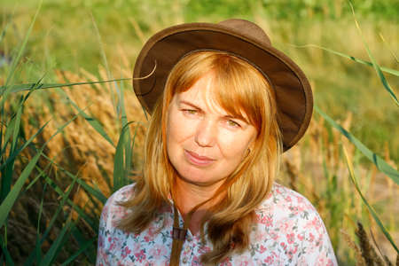 Defocus outdoor portrait of a beautiful blonde middle-aged woman near reed and pampas grass. Youth,...