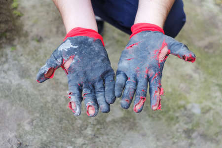 Defocus worn dirty and leaky gloves. Open palms of hands in worn workers gloves, protection against damage during operation, closeup on nature background. Poverty concept. Beggar. Out of focus.の写真素材