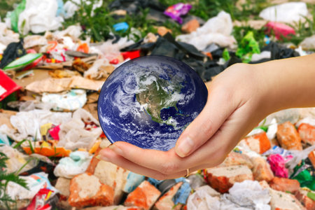 Defocus female hand holding planet globe on garbage background. Environmental protection concept. Earth in hands. Save of Earth. Elements of this image furnished by NASA. Out of focus.の写真素材