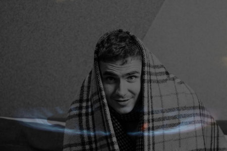 Defocus man wearing blanket. Flag European Union. Increase in the cost of gas bill. Soaring energy prices. Increase in the price of natural gas. Energy crisis in Europe. Out of focusの写真素材
