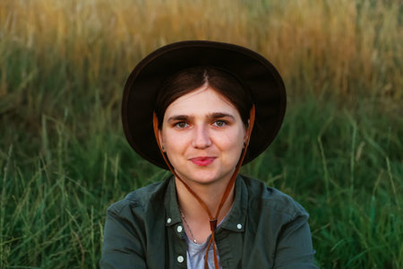 Defocus smiling young woman in cowboy hat. Girl in a cowboy hat in a field. Sunset. Nature background. Closeup portrait caucasian girl. Summertime. Fashion. Out of focus.の写真素材