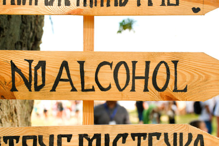 Defocus no alcohol sign is on a wooden board. no alcohol sign over a crowded street background. Stop to drink symbol prohibited icon. Refuse to be dependent. Out of focus.の写真素材