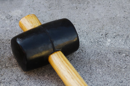 Defocus paving hammer close up. Garden brick pathway. Laying gray concrete paving slabs in courtyard...