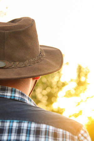 Back view of a young man wearing a cowboy hat. Young cowboy looking on sky away. Adventure western concept. Sunset.の写真素材
