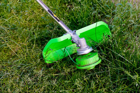 Defocus grass trimmer. A man mowing the grass. Outdoor view of a lawn trimmer mower cutting grass in...