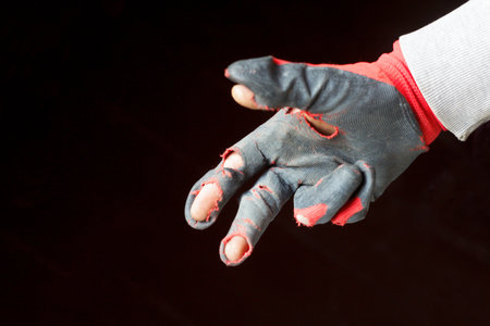 Demaged glove. Defocus worn dirty and leaky gloves. One male hand in worn workers gloves, protection against damage during operation, closeup on background. Out of focus.の写真素材