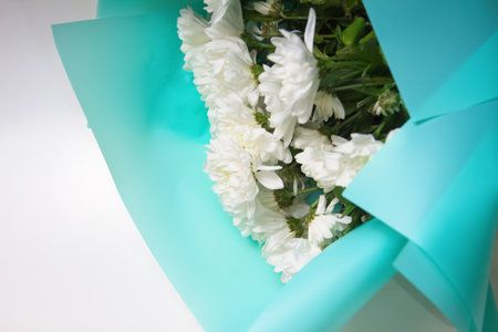 White daisy flowers bouquet on white background close up. Blue wrapped paper. Design template. Out of focus.の写真素材
